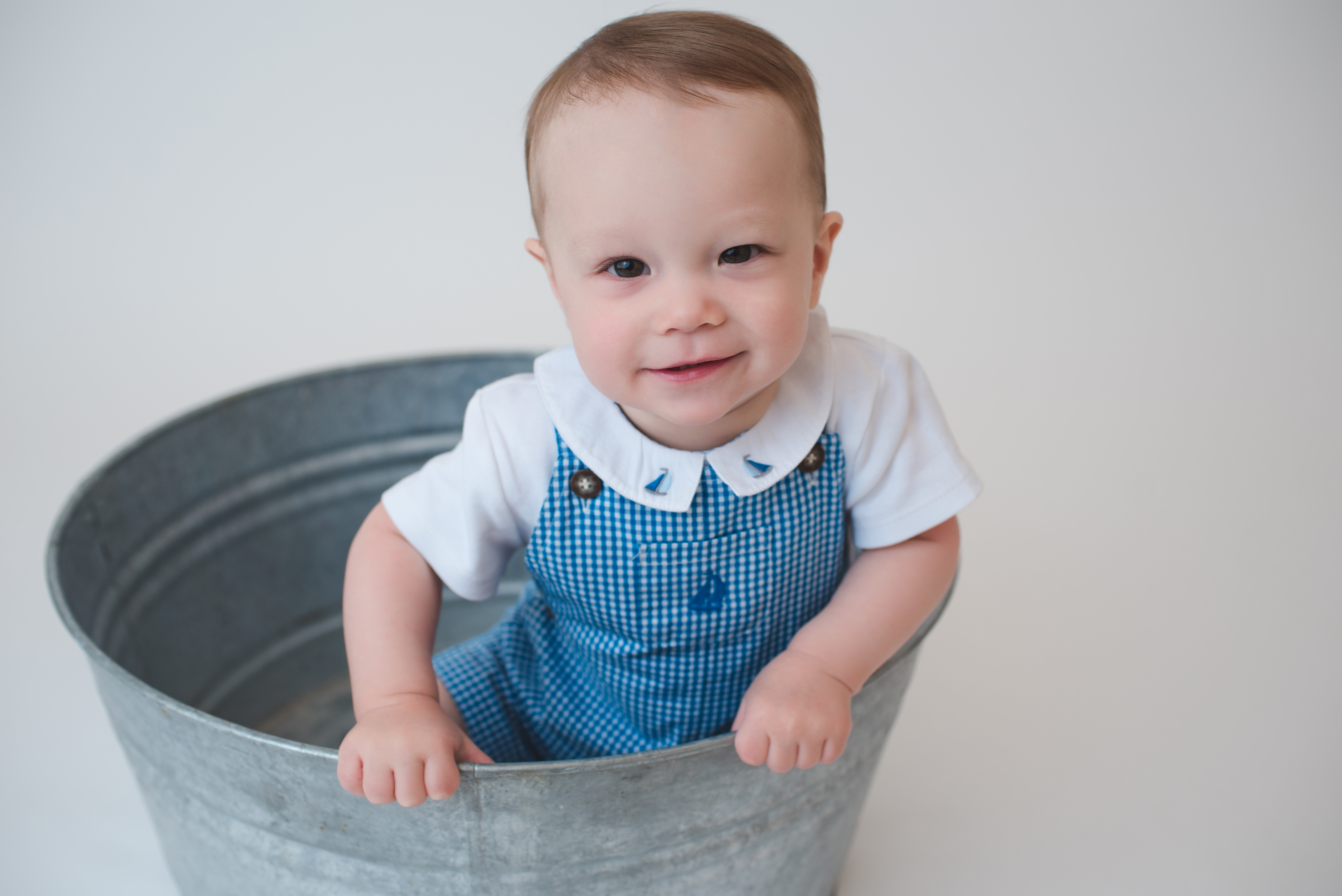smiling baby boy pulling himself up, bucket